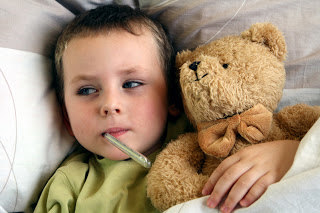 Boy in bed with a thermometer and a teddy bear