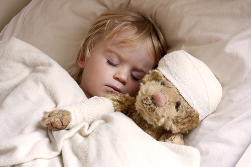 Baby sleeping with a bandaged teddy bear