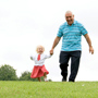 Grandfather running down a hill holding hands with a little girl